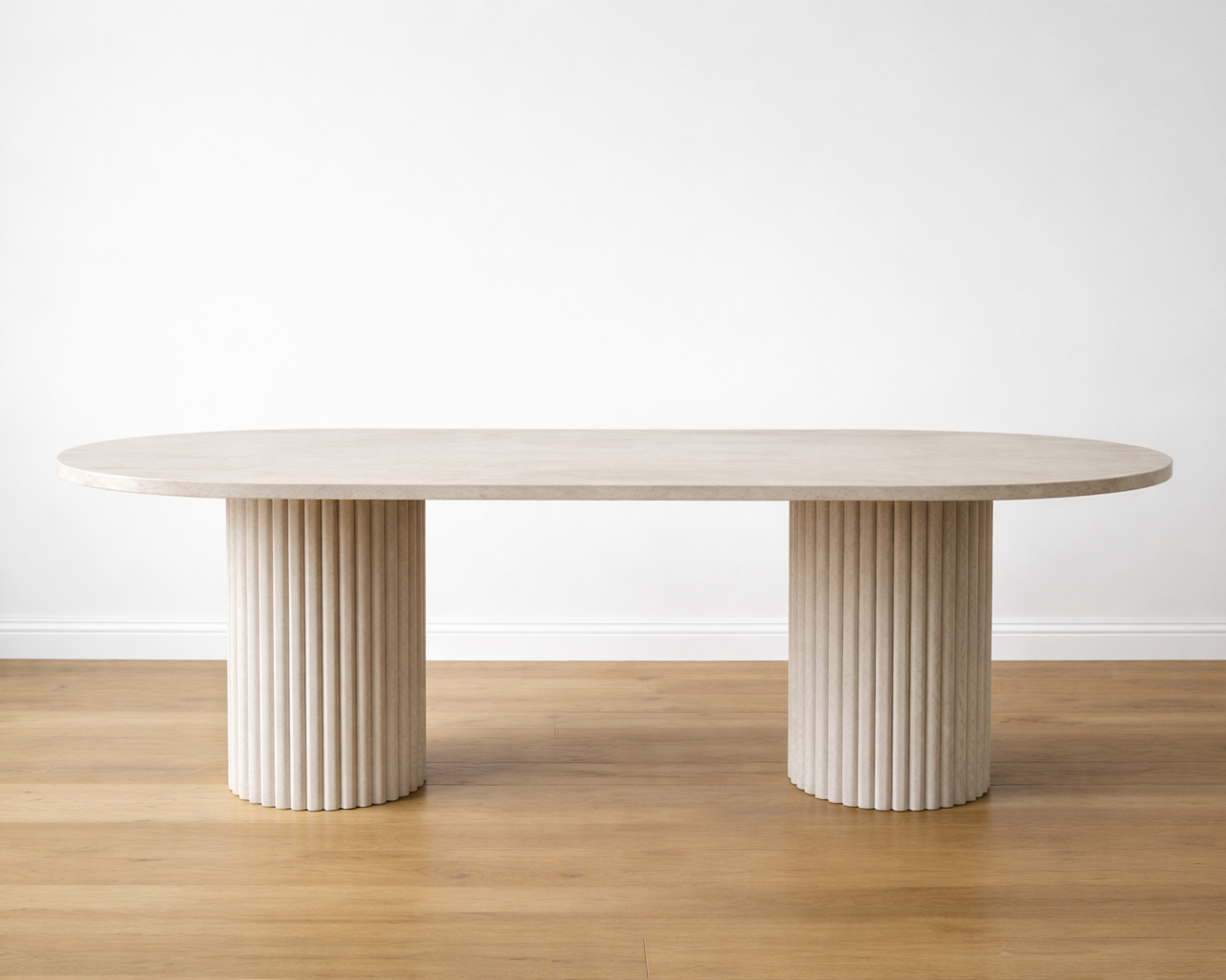 Modern oval marble dining table with cylindrical legs on a wooden floor and white wall background
