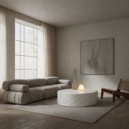 Modern living room with a gray sofa, round marble coffee table, and abstract painting.