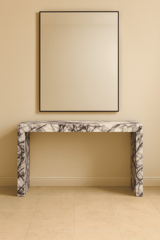 Marble console table against a beige wall with a framed mirror above it.