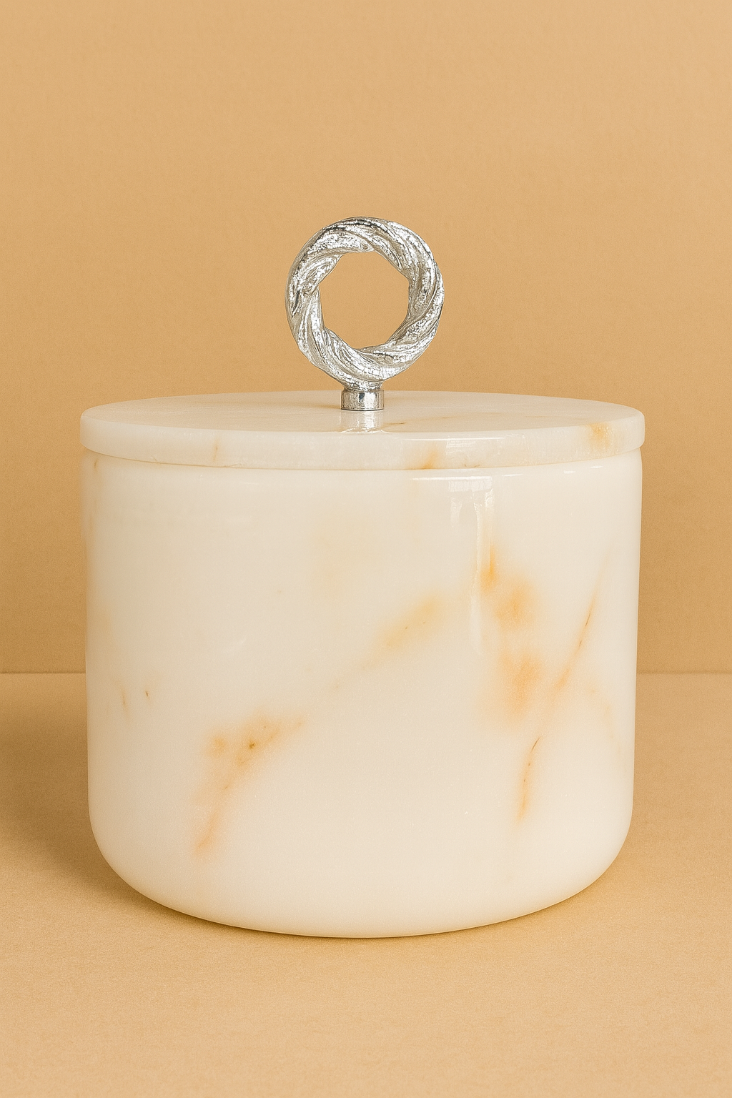 White marble jar with a silver lid on a beige background