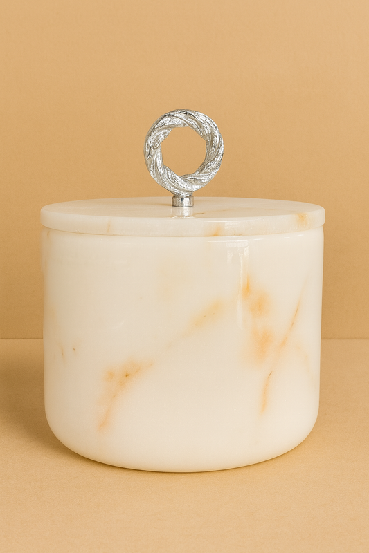 White marble jar with a silver lid on a beige background