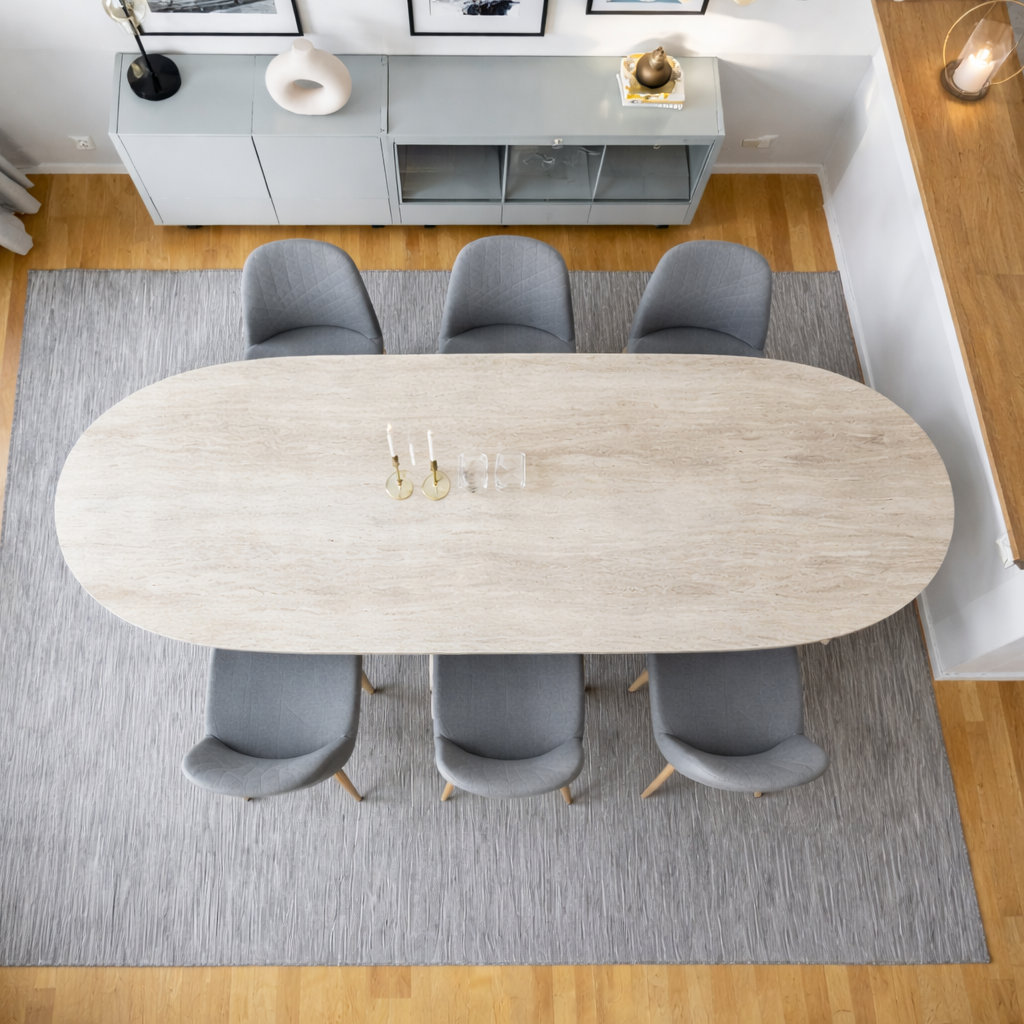 Dining room with an oval travertine table and gray chairs on a gray rug.