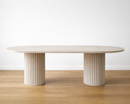 Modern oval marble dining table with cylindrical legs on a wooden floor and white wall background
