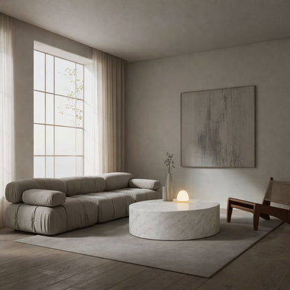 Modern living room with a gray sofa, round marble coffee table, and abstract painting.