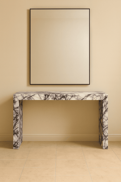 Marble console table against a beige wall with a framed mirror above it.
