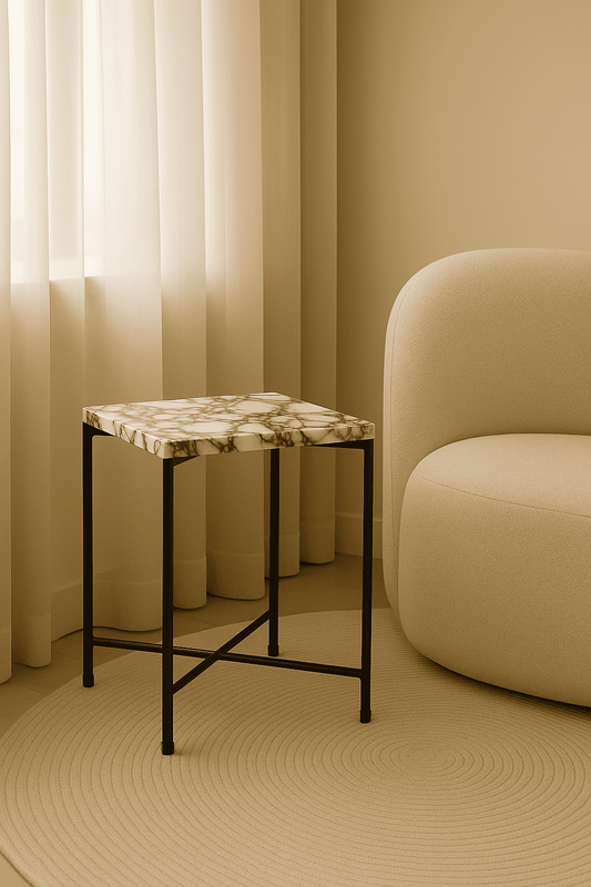 Small marble-top side table in a room with beige walls and a chair.