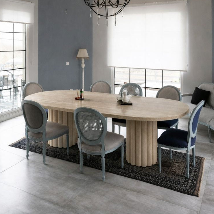 Modern dining room with a round travertine marble  table and chairs under a chandelier.