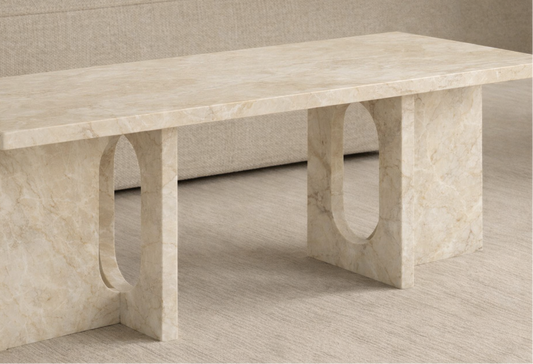 Beige marble table with unique curved legs on a neutral background