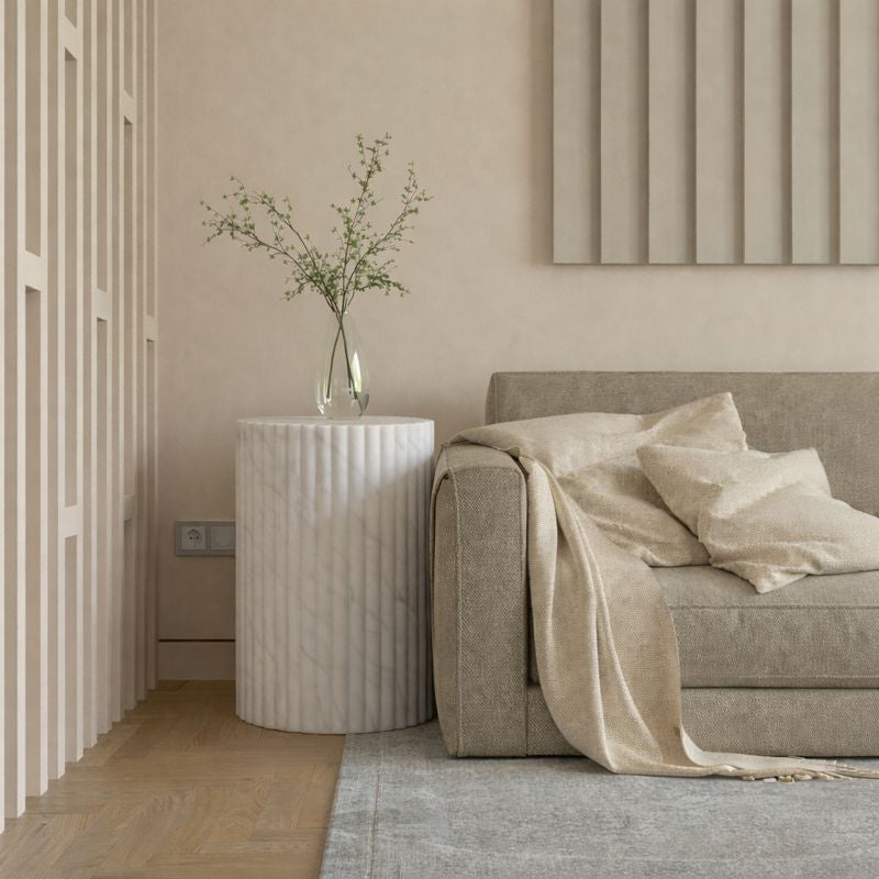 Modern living room with a beige sofa, decorative vase, and marble carrara side table.