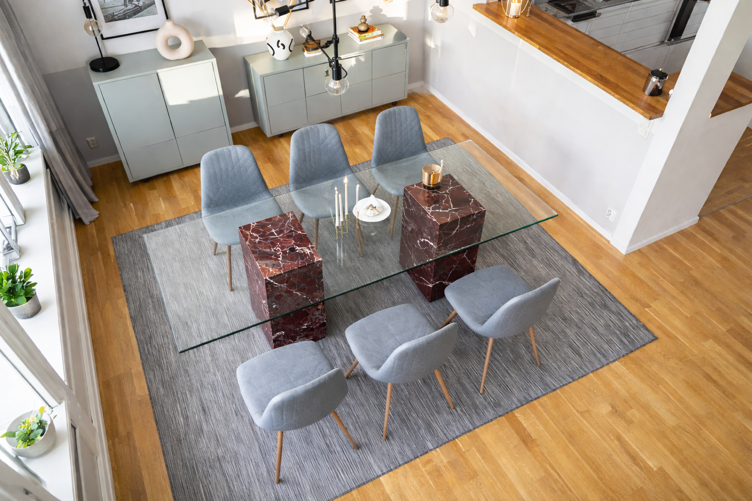 Modern dining room with a glass and marble table and gray chairs on a wooden floor.