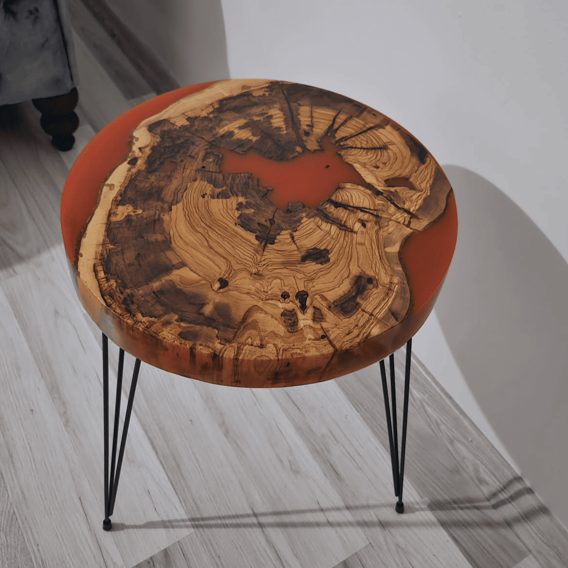 Round wooden side table with a natural finish on a light wooden floor.