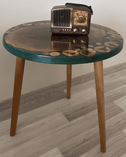 Round wooden table with a green top and a vintage radio on it, against a plain wall.