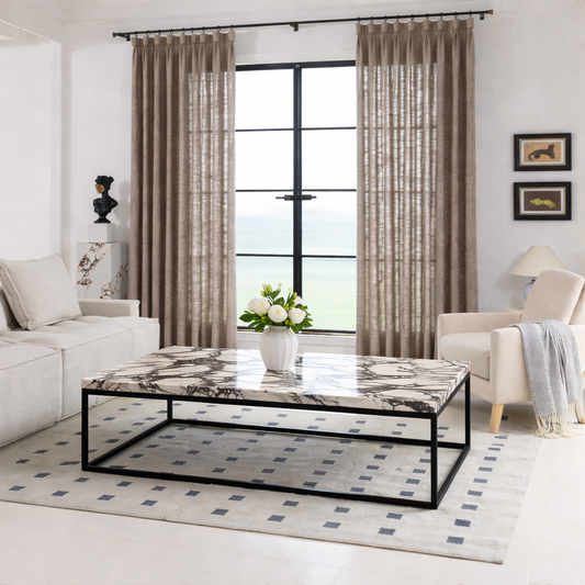 Modern living room with a marble coffee table, beige sofa, and patterned rug.